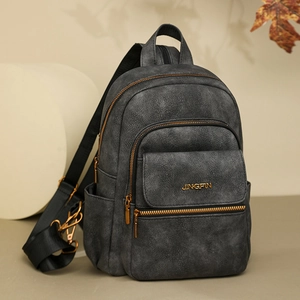 Close-up of deep gray matte leather backpack with gold metal zippers and brand logo