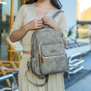 Detail of grey multi-pocket backpack showing Jingpin metal logo and faux leather texture