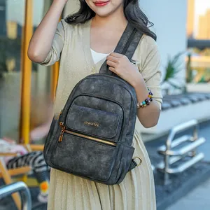 Detail view of dark grey leather backpack with gold zippers and premium textured finish