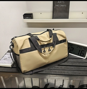 Detalle de la bolsa de gimnasio caqui y negra sobre mesa metálica en ambiente moderno
