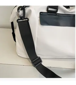 Detail of adjustable black nylon shoulder strap and premium logo on white travel bag