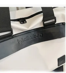 Detail of white textured fabric with black leather trim and embossed brand logo on travel bag