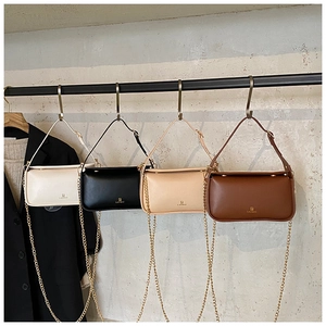 Détail de quatre sacs bandoulière en beige, noir, crème et café avec des chaînes dorées