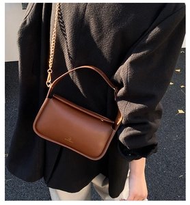 Gros plan d'un sac baguette en cuir marron rétro avec une bandoulière en chaîne dorée