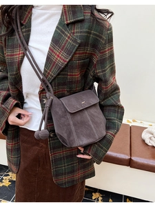 Détail du sac seau en daim gris foncé avec boucle métallique et breloques latérales