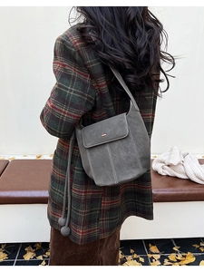 Détail du sac seau gris foncé avec surpiqûres blanches sur l'épaule du mannequin en automne