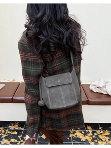 Détail du sac bandoulière gris foncé avec surpiqûres blanches et charm en forme de boule