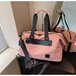 Detail view of the pink gym bag with black straps and brand logo in a sunlit room