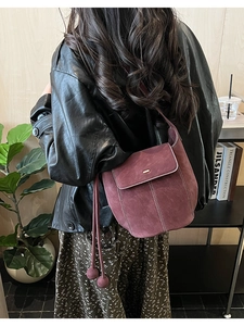 Gros plan sur un sac seau vintage en daim bordeaux avec surpiqûres blanches