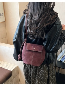 Détail du sac seau bordeaux en daim avec surpiqûres blanches et breloques boules
