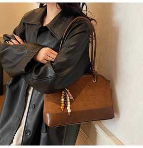 Κοντινό πλάνο ρετρό καφέ τσάντας με αντίθεση σουέτ δέρματος και κρεμαστό με χάντρες