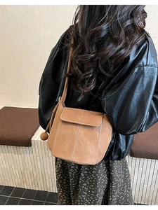 Détail du sac seau marron présentant des surpiqûres visibles et un fermoir minimaliste