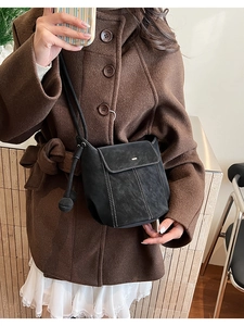 Détail du sac seau noir en daim avec surpiqûres blanches et boucle métallique dorée