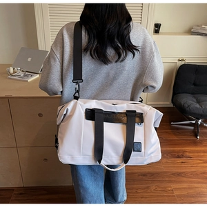 Close-up of white travel bag with adjustable strap and leather logo patch detail