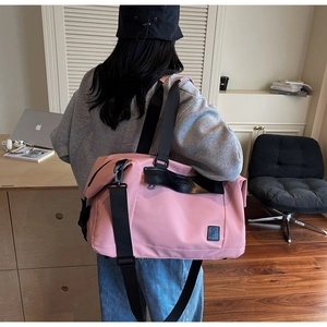 Rear view of a model carrying a pink large capacity travel duffel bag in a studio room
