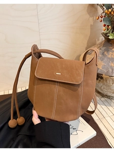 Détail du sac seau en cuir marron avec surpiqûres contrastées et boucle métallique