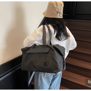 Close-up of black travel bag with magnetic flap pocket and shoulder strap details