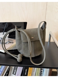 Détail du sac seau vert sauge avec surpiqûres blanches contrastées et breloques boules rondes