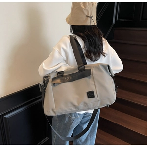 Rear view of a grey large capacity travel bag with leather pocket on wooden stairs