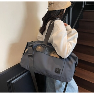 Detail view of the large capacity travel bag worn over the shoulder in a lifestyle setting