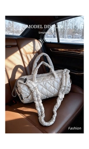 Detail view of a silver quilted down tote bag on a leather car seat with snow background