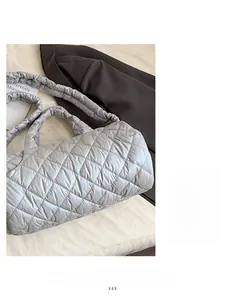 Detail of silver quilted cylinder tote bag with ruched strap and metallic finish