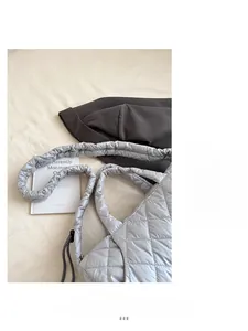 Close-up of a silver quilted puffer tote bag with metallic finish and fluffy straps