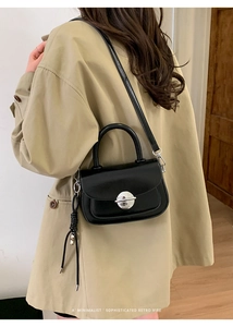 Detail of minimalist black leather retro handbag with silver buckle and knot charm