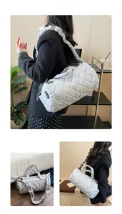 Detail of grey quilted down cylinder bag showing diamond stitching and adjustable strap