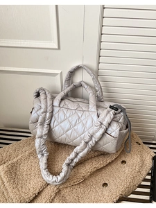 Detail of silver quilted puffer bag with chic ruched strap and textured diamond stitching