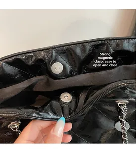 Detail of the strong magnetic buckle closure on a quilted patent leather tote bag