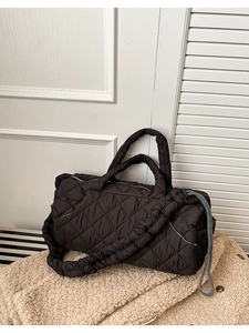 Macro shot of black quilted nylon tote bag with pleated strap on soft fleece texture