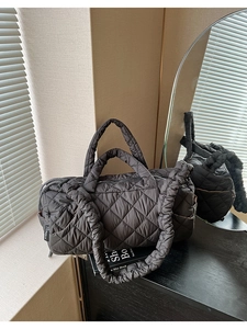 Detailed close-up of quilted black nylon tote bag with drawstring shoulder strap design