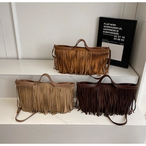 Trois sacs à main en daim à franges en beige, jaune et café sur des marches en marbre