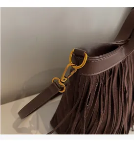 Détail du sac cabas en daim marron foncé avec franges et boucles en métal doré