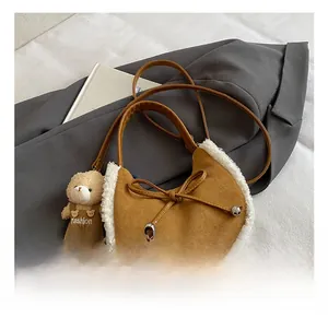 Close-up of brown suede crescent bag featuring white faux fur trim and bow details