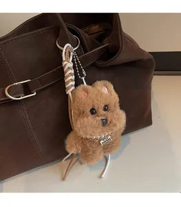 Detailansicht eines braunen Plüschhund-Anhängers mit Perlenkette an Ledertasche