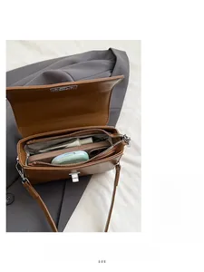 Detailweergave van het ruime interieur en ritsvak van de bruine leren crossbody schoudertas