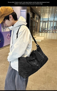Bolso de viaje negro moderno con tejido texturizado mostrado por modelo en centro comercial