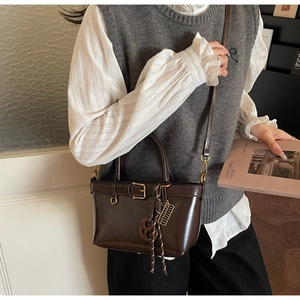 Detailweergave van een donkerbruine vintage emmertas crossbody gedragen met decoratieve gesp