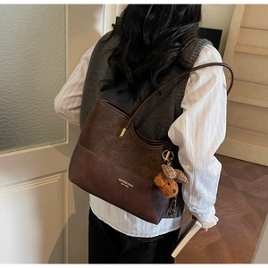 Detail of vintage brown tote bag showing textured patchwork leather and golden logo
