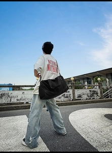 Black large capacity travel bag for sports and gym shown in an outdoor street setting