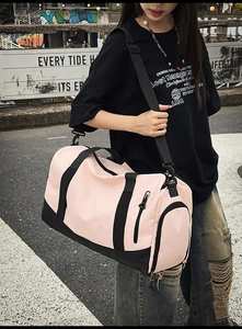 Street-style view of a pink and black gym bag with shoe compartment and shoulder strap
