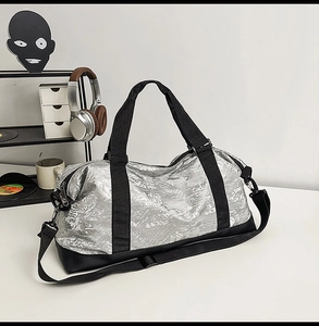 Vista detallada de la bolsa de deporte plateada con correas negras y bandolera ajustable