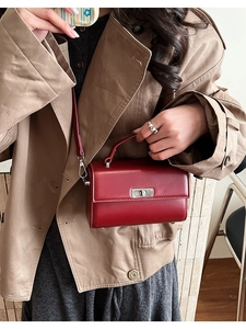 Detail van een retro bordeauxrode crossbodytas met zilveren draaisluiting en een matte afwerking