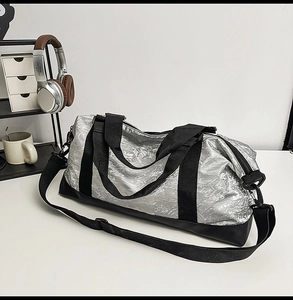 Detalle del bolso de viaje plateado con textura arrugada impermeable y correas en negro