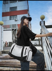 Outdoor shot of a black and white sports gym bag with independent shoe compartment and strap