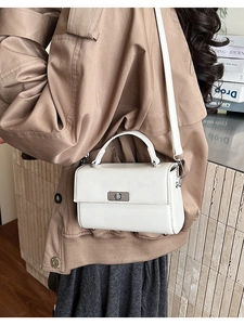 Witte crossbodytas getoond met een stijlvolle kaki trenchcoat voor een moderne uitstraling