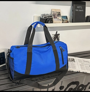 Detail view of a blue sports duffel bag with a spacious main compartment on a black bench