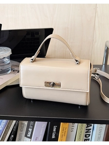 Detailopname van de minimalistische roomwitte crossbody tas met metalen draaislot